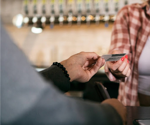Bartender checking a customer's ID before serving alcohol at the bar